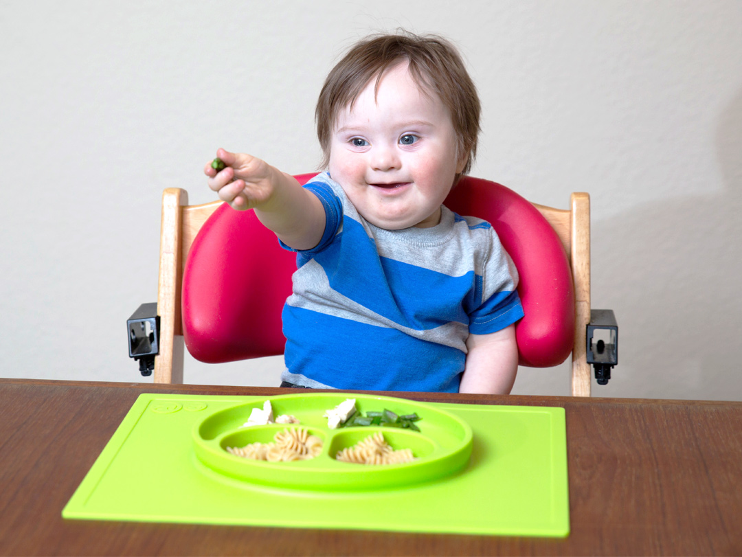 little boy with Downs Syndrome enjoying lunch with his ezpz Happy Mat. Giving back by Hip Mommies