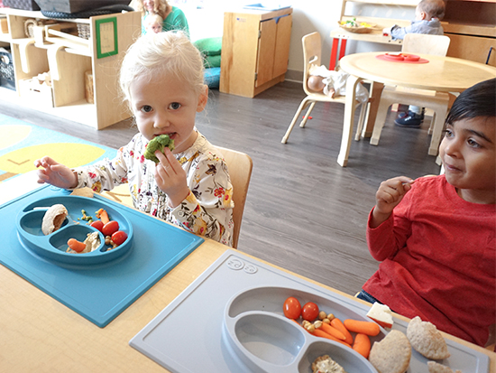 two year old friends at their child care centre trying broccoli with ezpz