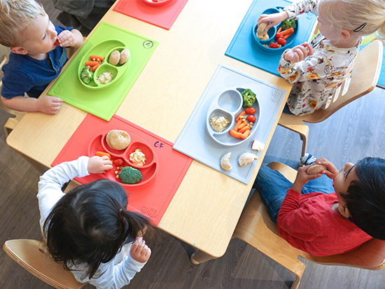 group of children in a child care centre eating with ezpz Happy Mats