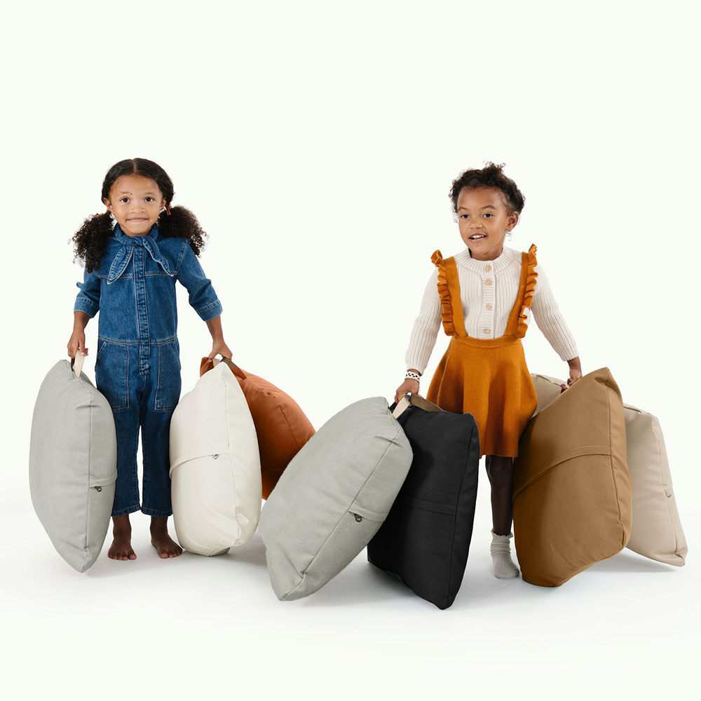 two small girls holding handfuls of Gathre mini floor cushions