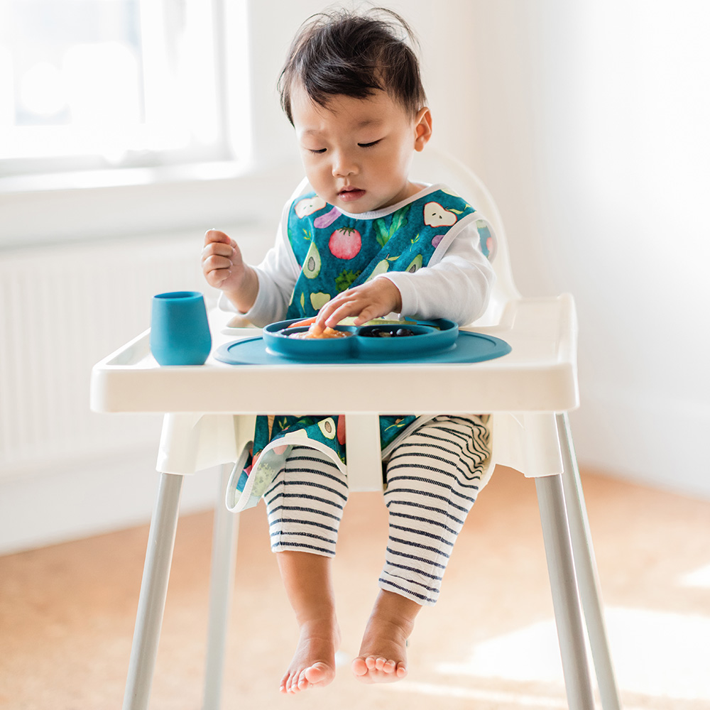 9 month old boy eating lunch in an highchair from an ezpz mini mat