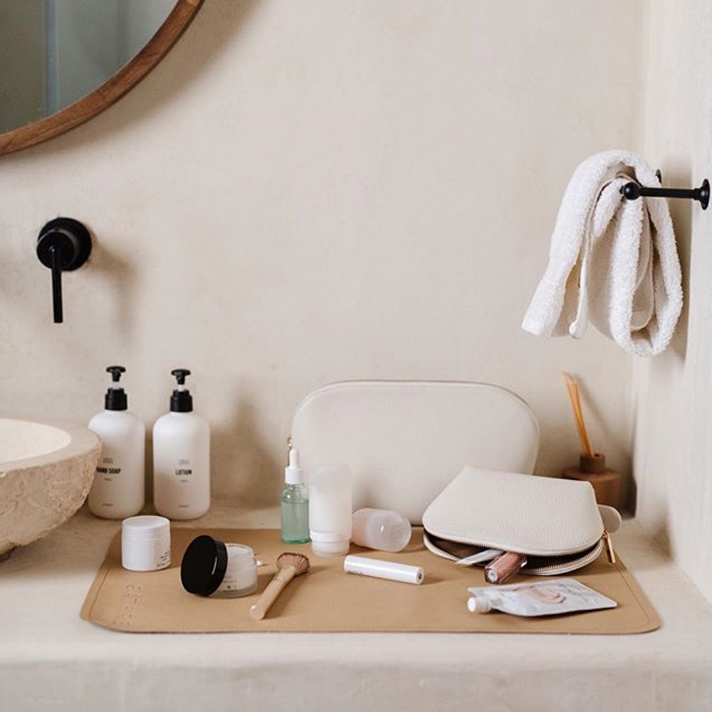 makeup and toiletries spread out on a Gathre micro mat in a modern bathroom