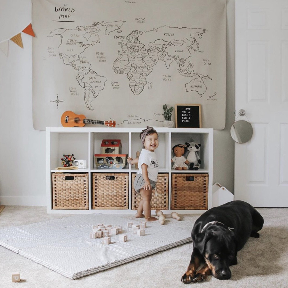 toddler girl and her dog in a playroom with a padded Gathre mat on the floor and a World Map on the wall