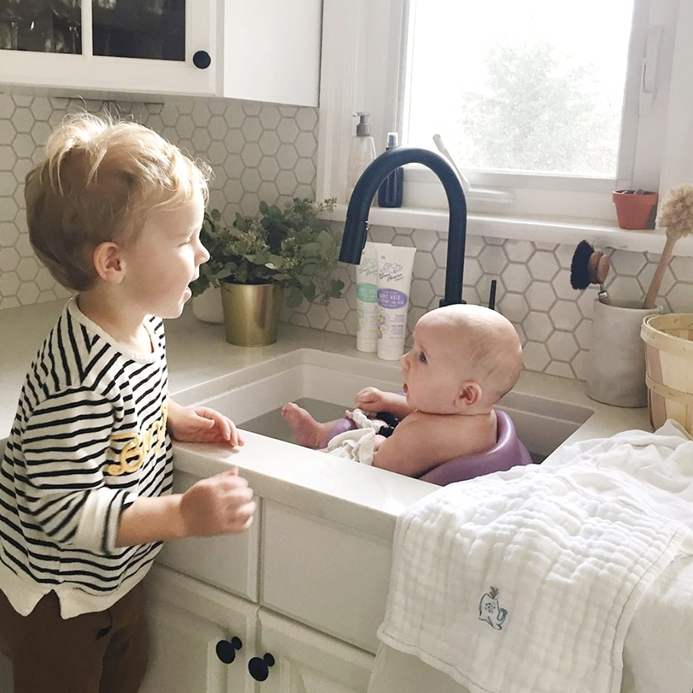 a little boy bathing his baby sister in the sink with Green Beaver Baby Products