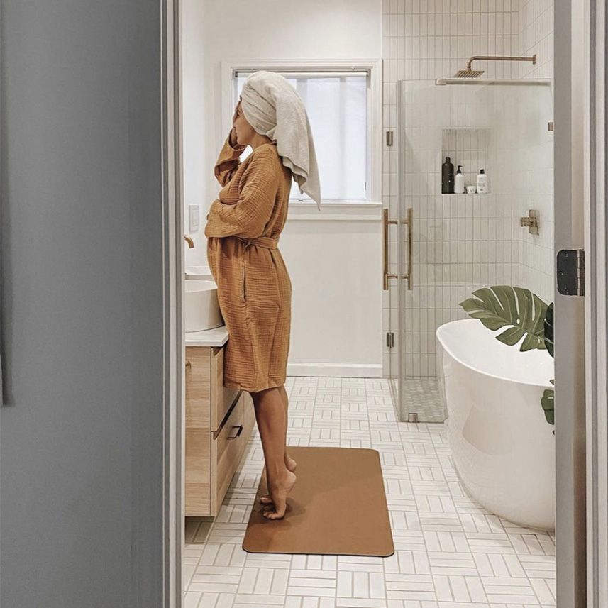 woman in a bathrobe and towel standing on a Gathre Home Mat in a modern bathroom